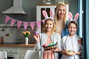 mère heureuse et ses enfants souriants et adorables tenant des œufs colorés et joyeuses pâques véritablement photo