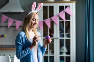 belle blonde souriante dans les oreilles de lapin couleurs oeuf de pâques, se prépare pour pâques photo