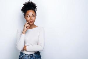 Une fille afro-américaine pensive se dresse sur un fond de biome, en détournant les yeux
