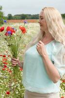 magnifique âge moyen blond femme des stands parmi une floraison champ de coquelicots photo