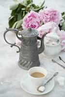 ancien encore la vie avec une tasse de café contre une bouquet de rose pivoines photo