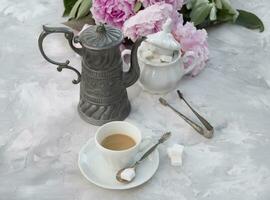 ancien encore la vie avec une tasse de café contre une bouquet de rose pivoines photo