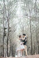 couple romance avec énorme , porter engagement pose rapide avec pied pop parmi sec des arbres dans le parc photo