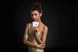 femme gagnant - Jeune femme dans une chic or robe en portant deux as, une poker de as carte combinaison. photo