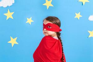 peu enfant pièces super-héros. enfant sur le Contexte de brillant bleu mur avec blanc des nuages et étoiles . fille Puissance concept. photo