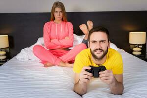 Jeune couple ayant en jouant jeux vidéos dans lit photo