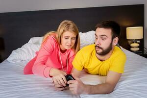 Jeune couple ayant en jouant jeux vidéos dans lit photo