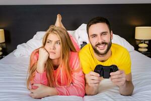 Jeune couple ayant en jouant jeux vidéos dans lit photo