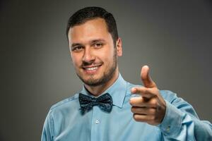 souriant homme est faire des gestes avec main, montrer du doigt doigt à caméra photo