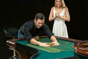 Jeune couple célébrer gagner à roulette table dans casino. photo
