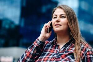 jolie femme parlant au téléphone sur le fond d'un fond de ville moderne photo