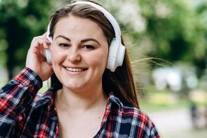 jeune femme portant des écouteurs avec un visage heureux debout au milieu du parc photo