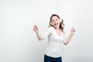 fille d'énergie avec des écouteurs blancs écoutant de la musique avec les yeux fermés sur fond blanc en studio. photo