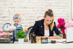 maman et femme d'affaires travail avec portable ordinateur à Accueil et en jouant avec sa bébé fille. photo