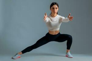 sportif fille Faire poids latéral Divisé squats sur gris Contexte photo