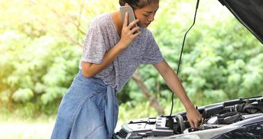 femme asiatique utilisant un téléphone portable tout en regardant un homme stressé assis après une panne de voiture dans la rue photo