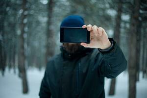 Beau barbu homme fait du selfie dans forêt dans hiver photo