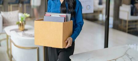 quitter emploi asiatique affaires femme Envoi en cours démission lettre et emballage des trucs démissionner déprimer ou porter affaires papier carton boîte dans bureau. changement de emploi ou mis à la porte de entreprise photo