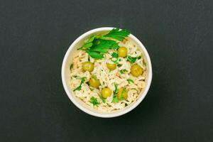 préparé instant nouilles avec vert pois et légumes verts sur noir Contexte Haut voir. rapide le déjeuner ou mauvais pour la santé vite nourriture photo