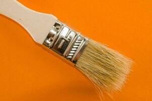 une brosse avec une blanc manipuler sur un Orange Contexte photo