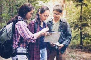 groupe asiatique de jeunes faisant de la randonnée avec des sacs à dos d'amis marchant ensemble et regardant la carte et prenant un appareil photo au bord de la route et ayant l'air heureux, détendez-vous en voyage de concept de vacances