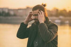 Jeune moderne homme d'affaire est ayant une mal de crâne tandis que séance par le rivière.tonique image photo