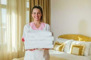 portrait de magnifique Hôtel Femme de ménage en portant nettoyer et Frais les serviettes. photo