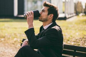 élégant homme d'affaire jouit en buvant café tandis que séance extérieur.tonique image. photo
