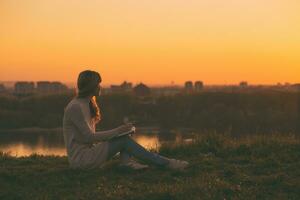 femme jouit l'écriture à sa carnet avec une le coucher du soleil plus de le ville. photo