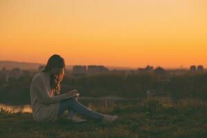 femme jouit l'écriture à sa carnet avec une le coucher du soleil plus de le ville. photo