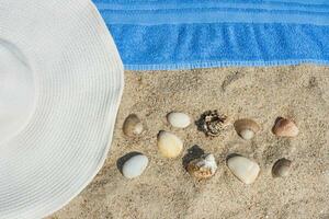 chapeau, coquilles, et une serviette sur le plage photo