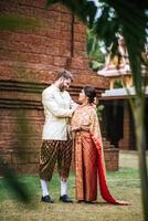 la mariée asiatique et le marié caucasien passent un moment romantique avec une robe thaïlandaise photo