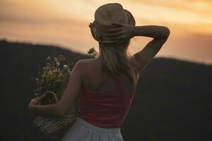 femme en portant panier avec fleurs et jouit à la recherche à magnifique le coucher du soleil. photo
