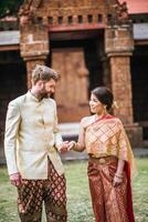 la mariée asiatique et le marié caucasien passent un moment romantique avec une robe thaïlandaise photo