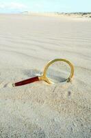 une grossissant verre est mensonge sur le le sable dans le désert photo