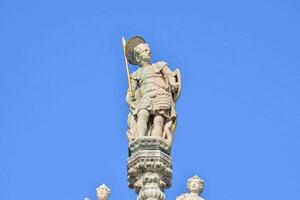 statue de une homme en portant une épée et bouclier sur Haut de une bâtiment photo