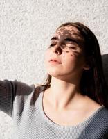 portrait d'une belle jeune femme avec un motif d'ombre sur le visage et le corps sous forme de fleurs photo