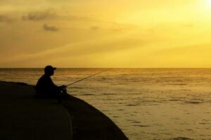 silhouette de homme pêche sur une lac. photo