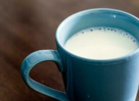 lait dans une tasse bleue sur la table en bois et en verre supérieure photo