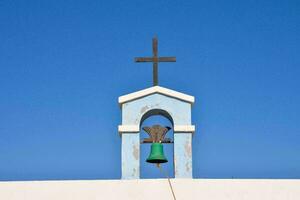 une cloche sur Haut de une blanc mur avec une traverser photo