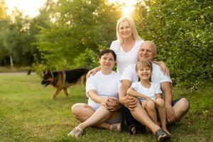 portrait de un élargi famille avec leur animal de compagnie chien séance à le parc photo