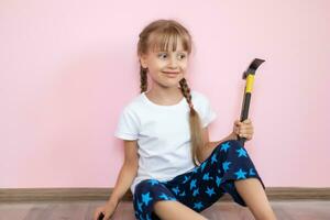 peu fille avec une marteau fait du réparations dans le enfants pièce photo