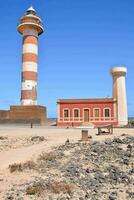 une phare sur le plage avec une rouge bâtiment photo