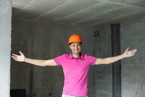 profession, construction et bâtiment - content souriant ouvrier ou constructeur dans casque plus de pièce avec travail équipement à Nouveau Accueil ou appartement Contexte photo