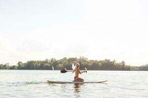 action coup de Jeune femme sur pagayer planche photo