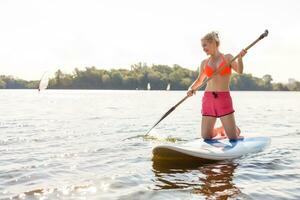 Jeune attrayant femme sur supporter en haut pagayer planche dans le lac, souper photo