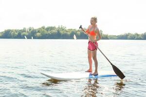 Jeune attrayant femme sur supporter en haut pagayer planche dans le lac, souper photo