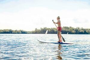 action coup de Jeune femme sur pagayer planche photo