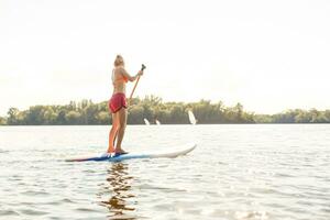 action coup de Jeune femme sur pagayer planche photo