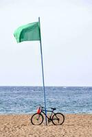 une vélo est garé sur le plage avec une vert drapeau photo